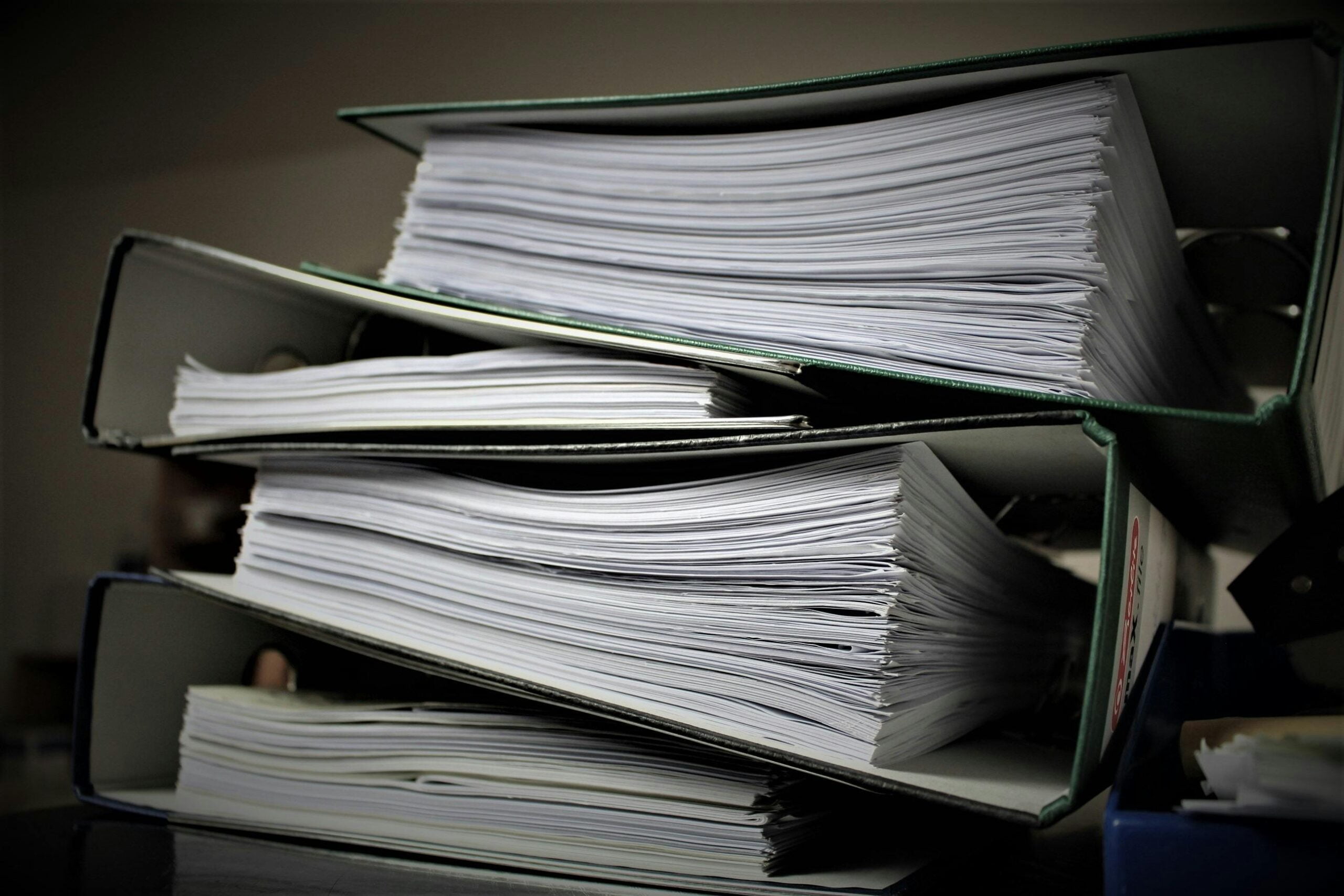 rear view of a stack of four binders, each full of paper